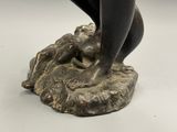 bronze statue of a woman holding a bird on a rock