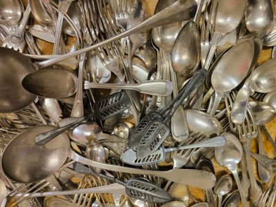 de nombreuses cuillères en argent et de nombreuses cuillères à soupe sur la table