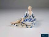 une figurine représentant une femme assise par terre avec un bol