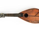 an old wooden guitar with writing on it sitting on a white surface