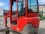 the back end of a small red excavator parked in a parking lot
