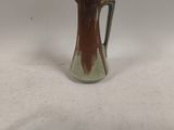 a brown and green glass pitcher sitting on top of a white table