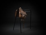 a brown leather bag sitting on top of a metal stand