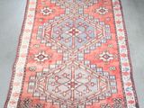 un vieux tapis aux motifs rouges et bleus posé sur un sol gris