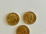 three gold coins sitting next to each other on a white surface