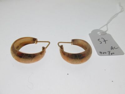 une paire de boucles d'oreilles créoles dorées sur un fond blanc