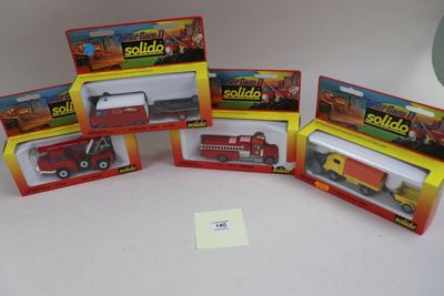 quatre jouets emballés, dont un camion de pompiers, un camion et un camion de pompiers