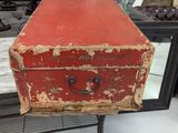 an old red suitcase sitting on a stand in front of a mirror