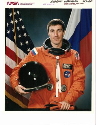 Un astronaute de la NASA en combinaison spatiale orange, tenant un casque et un drapeau américain