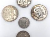 five different coins are arranged in a circle on a white surface