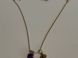 un gros plan d'un collier avec une pierre violette sur une chaîne
