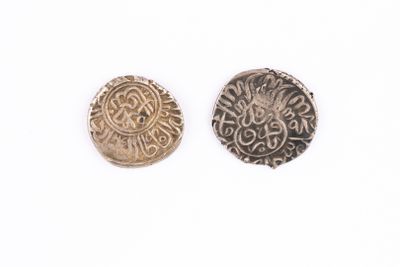 two silver and gold coins sitting next to each other on a white surface
