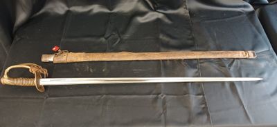 un gros plan d'une épée posée sur un tissu noir, sur une table