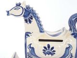 a blue and white horse shaped money box next to a white vase