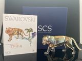 une figurine représentant un tigre posée sur une table, à côté d'un livre