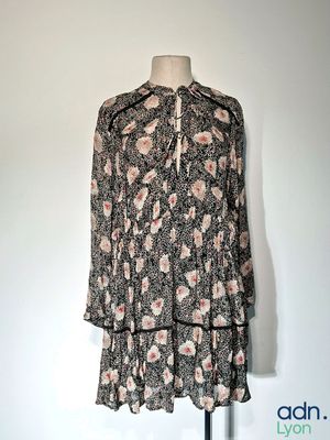 La robe est noire et blanche, avec des fleurs roses.