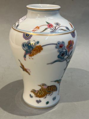 un vase blanc orné d'un oiseau et de fleurs