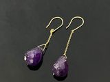 une paire de boucles d'oreilles en améthorate posées sur une surface noire