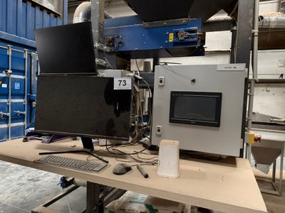 deux écrans et un clavier posés sur une table dans un entrepôt
