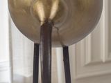 a gold vase sitting on a wooden table in front of a window