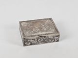 une vieille boîte en argent posée sur une surface blanche