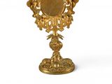 a gold mirror on a stand on a white background