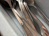 a lot of silver spoons and spoons in the sink