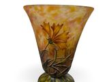 a glass vase with a flower on it on a white surface