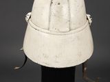 an old helmet on a black stand on a gray background