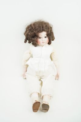 une image représentant une poupée aux cheveux bouclés et vêtue d'une robe blanche