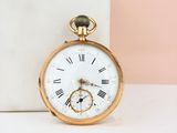 gold pocket watch with roman numerals on a marble block