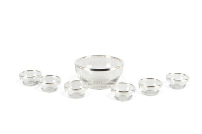 un saladier en verre et plusieurs verres posés sur une surface blanche