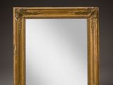 un miroir à cadre doré sur fond gris