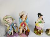 three figurines of women and a dog are sitting on a table