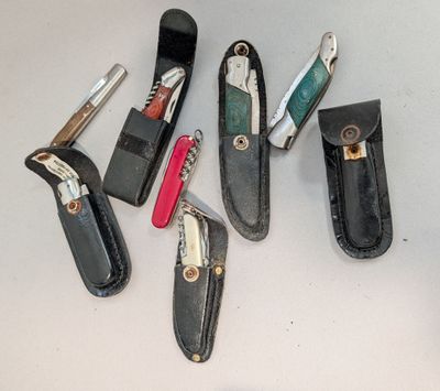 Plusieurs types de couteaux de poche sont disposés sur une table