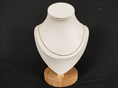 un gros plan sur un mannequin blanc orné d'une chaîne en or