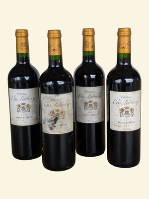 four bottles of wine are lined up on a white surface