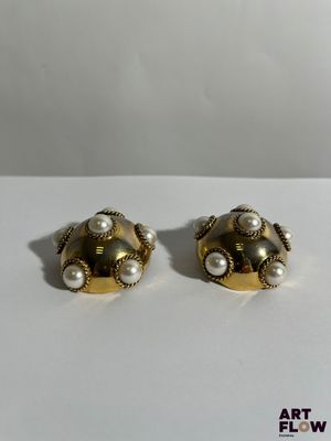 une paire de boucles d'oreilles en or et perles posées sur un fond blanc