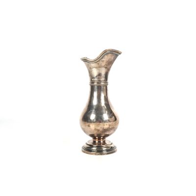 un vase en argent posé sur une surface blanche
