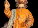 a wooden statue of jesus holding his hand up