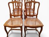 four wooden chairs with cane backrests are lined up against a white background