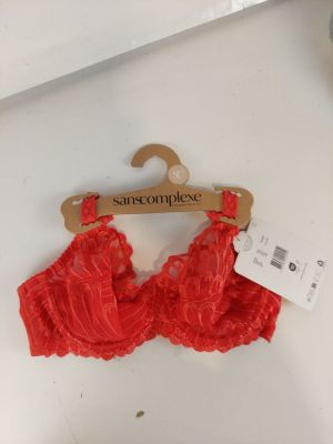 une bralette en dentelle rouge suspendue à un cintre, avec une étiquette de prix