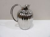 a silver pitcher sitting on a table with a white background