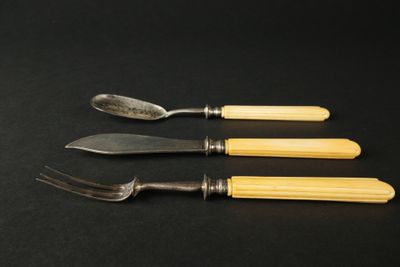 trois fourchettes et un couteau posés sur une table noire