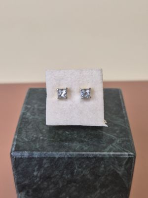 a pair of earrings sitting on top of a marble block