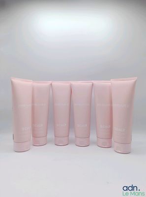 quatre tubes de lotion rose posés les uns à côté des autres sur une surface blanche