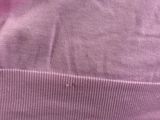the back of a pink sweater with a small hole in the middle of it