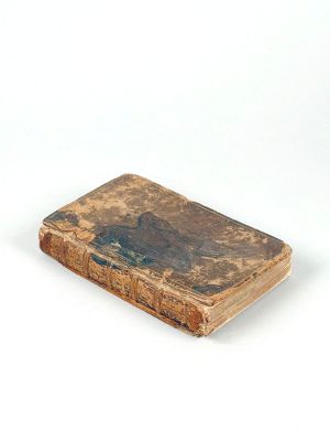 un vieux livre posé sur une table à côté d'un mur blanc