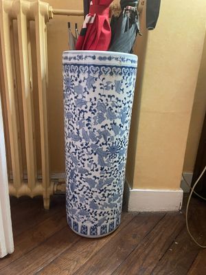 un grand vase bleu et blanc dans lequel se trouve un parapluie