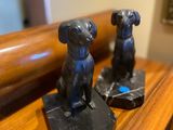 two statues of dogs sitting on top of a wooden table